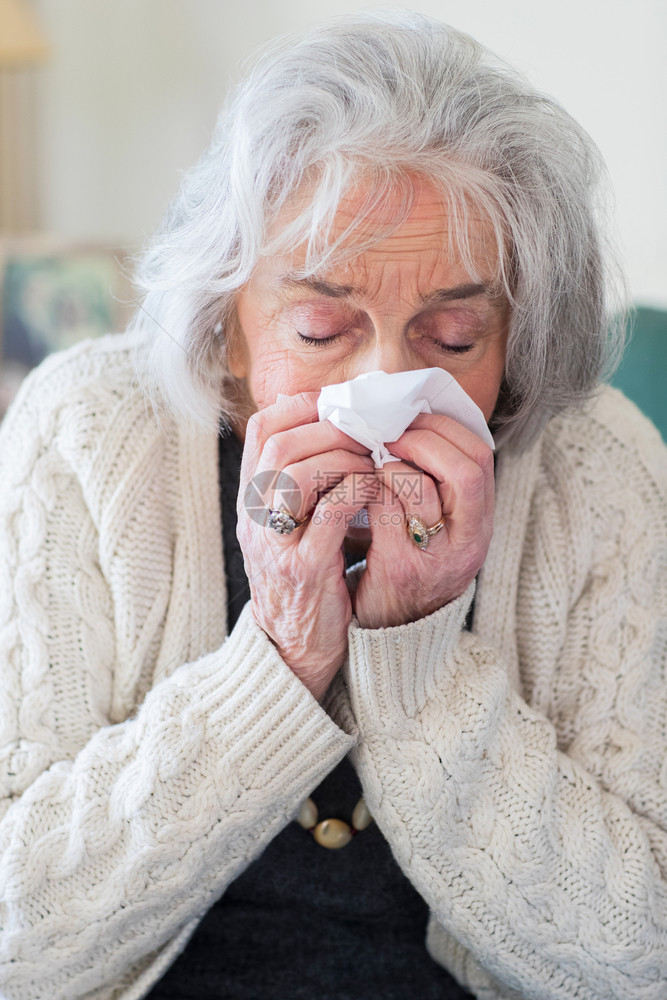 发烧家里吹流感鼻子的年长妇女手帕组织图片