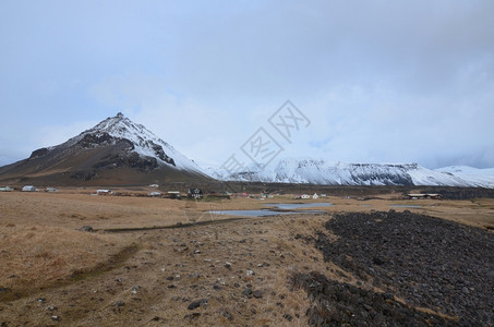 暴风云位于火山底的美丽Arnarstapi渔村景观乡的图片