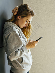 保持现代的一位年轻女子站在走廊上看着她的智能手机留言照片她写着学生图片