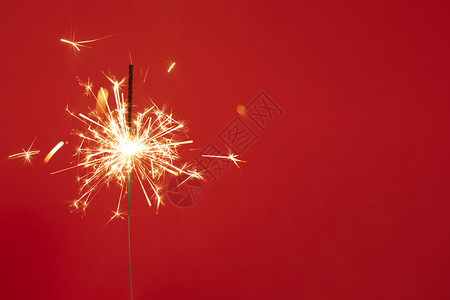 孟加拉颜色红背景的亮燃烧闪光灯与许多新年快乐的火花概念复制空间关闭红背景的亮燃烧闪光灯与大量火花的热圣诞节生日设计图片