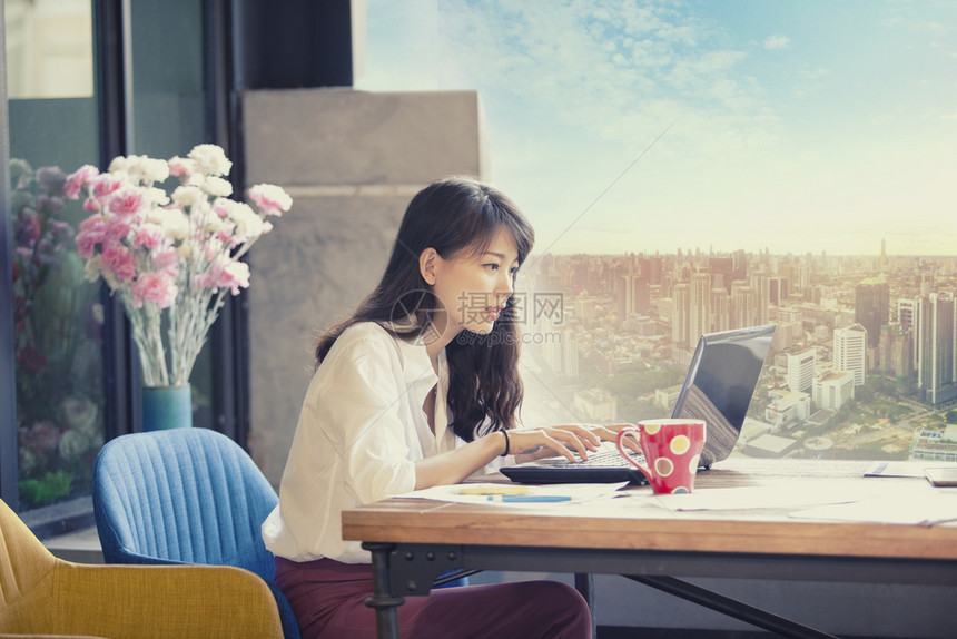 办公室桌面利用城市办公大楼背景从事计算机膝上型工作的亚洲自由职业者人数聊天图片