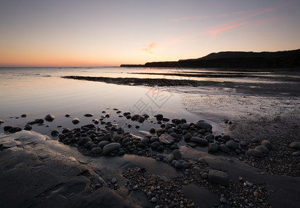 鹅卵石安详接触日落时的金梅里奇湾在英国格兰多尔塞海岸图片