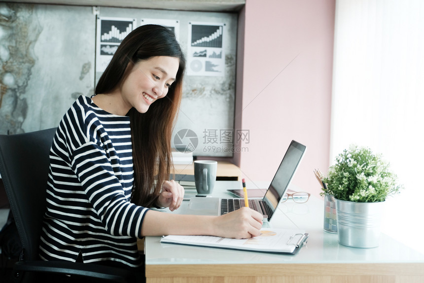 美丽的女士年轻亚洲商人在办公室用纸和笔记本电脑工作情绪快乐在家工作办公室临时生活方式概念从事书面和笔记本电脑工作在家里吸引人的图片