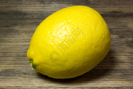 木板陈年黄色的制背景上一个黄色柠檬图片