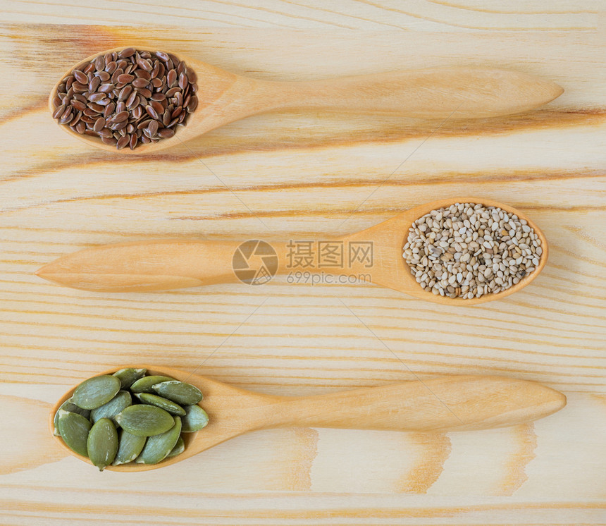 生的亚麻种子矿物质棕色麻白芝和南瓜的干成分种子木制勺餐桌顶视图图片
