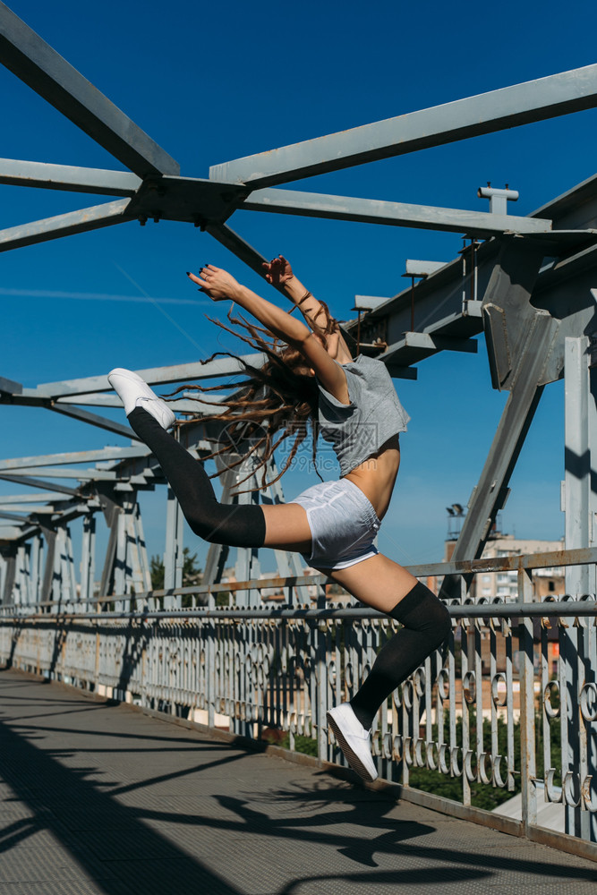 舞蹈吸引人的城市长头发年轻女孩在桥上装着图片