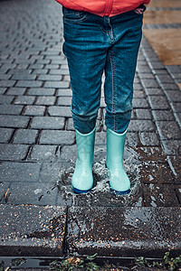 橡胶孩子下雨天阴沉秋日穿着胶靴跳进水坑的小女孩腿特写图片