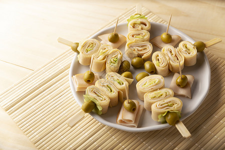 包裹零食配着火腿和奶酪的薄饼卷在一块装有橄榄的棍子上美食图片