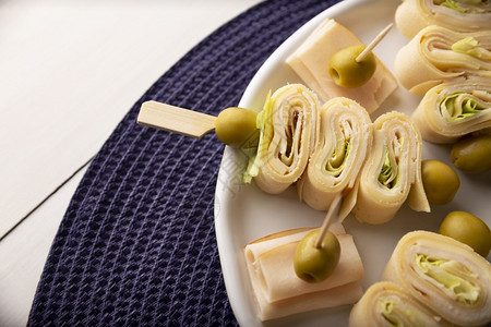 聚会林小型的配着火腿和奶酪的薄饼卷在一块装有橄榄的棍子上图片
