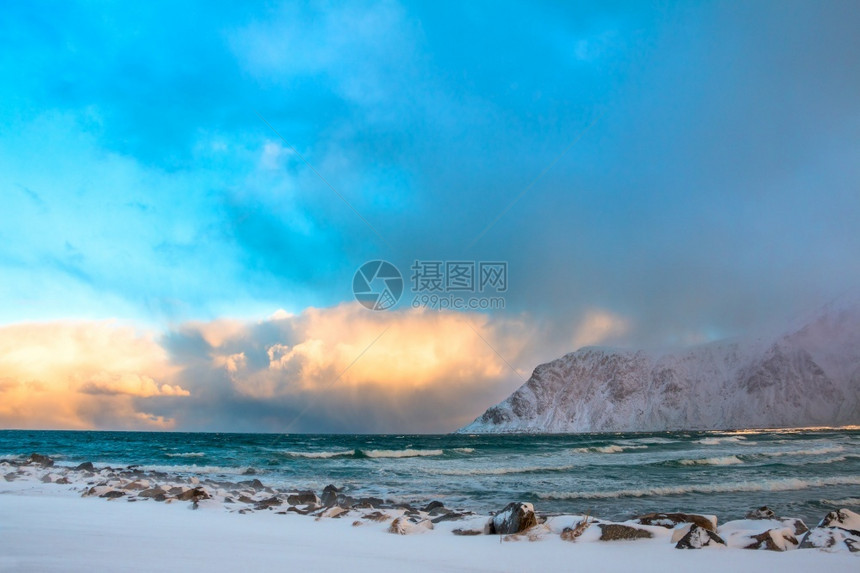 悬崖在挪威冬季海浪和有色云之间波长的彩风横扫于温冬挪威海冲浪和有色云之间冰罗弗敦图片