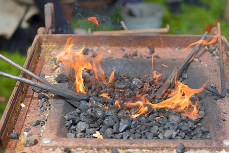 锤子用煤炭和火在户外铁匠边缘图片