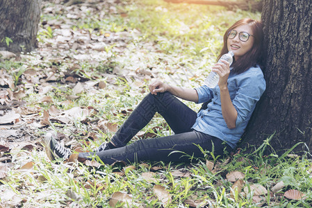 白色的阳光新鲜坐在公园旅行概念中的饮用水里年轻快乐的女旅行者图片
