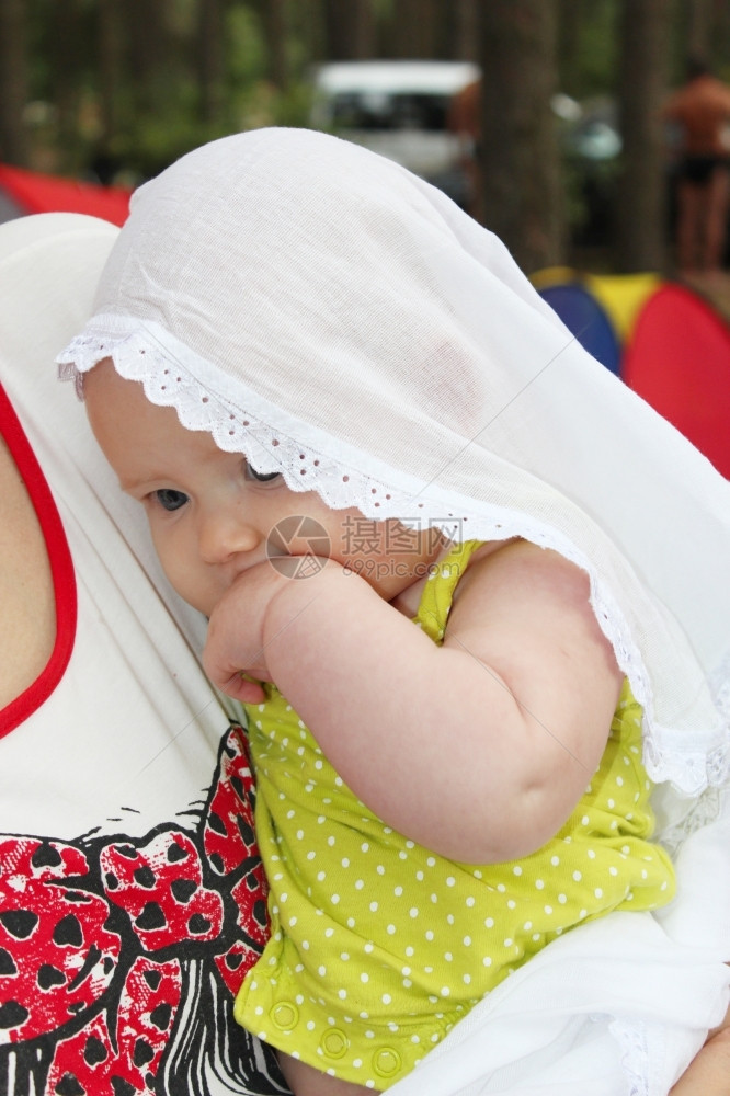女孩常设披风小婴儿在白色的毛发上小婴儿在白色的花纹上放在她母亲的手里图片