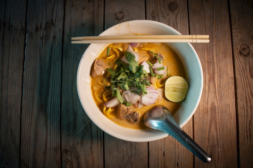 Khaosoi传统泰国美食KhaoSoi泰式咖喱面汤木桌上有鸡肉热的烹饪木头图片