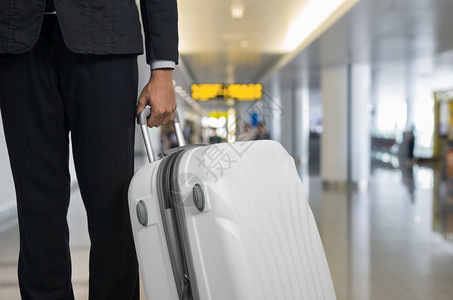 包飞机场假期出发休息室的商人和行李箱背景模糊的飞机暑假概念场候区的旅行者李箱和手提商家行李图片