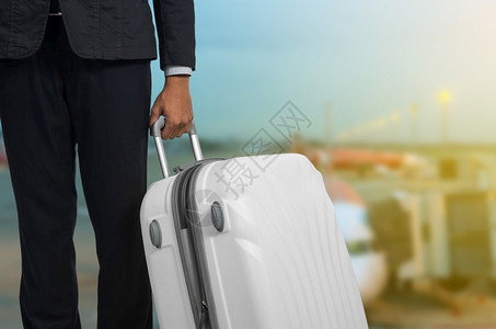 机场出发休息室的商人和行李箱背景模糊的飞机暑假概念场候区的旅行者李箱和手提商家行李假期携带运输图片