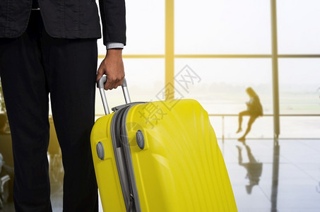 机场出发休息室的商人和行李箱背景模糊的飞机暑假概念场候区的旅行者李箱和手提商家行李男人乘客窗户图片
