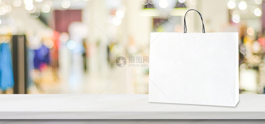 顾客为了站在白大理石桌上的色大理石桌上的白皮书购物袋在模糊的商店背景之上有复制空间商业营销背景横幅模拟零售板销产品购买图片