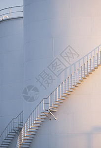 石化白色的商业储存油罐垂直框架的曲线螺旋楼梯表面阳光照亮图片