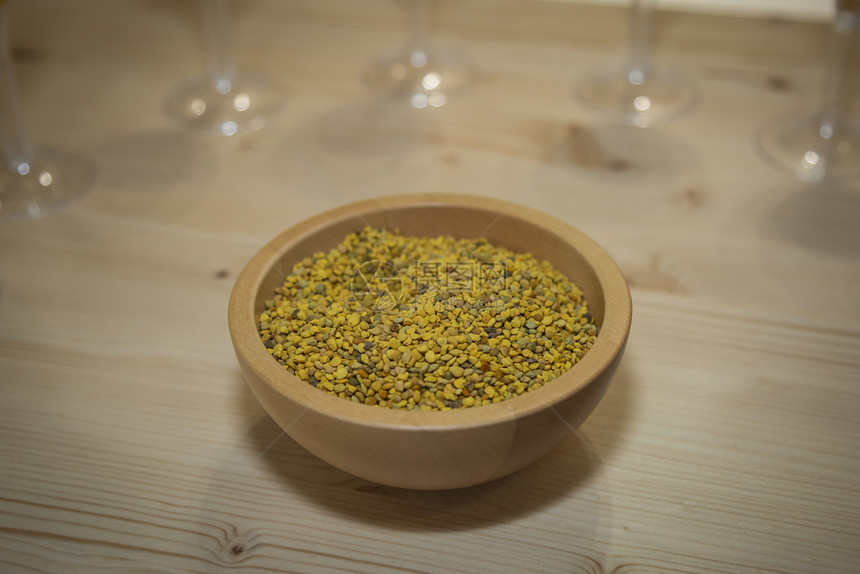 圆形的饮食维生素圆形木碗中蜜蜂的花粉圆形木碗中的绿色和黄小颗粒圆形木碗中的蜜蜂绿色和黄小颗粒的花粉图片