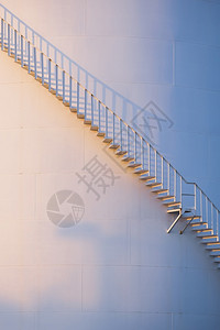在垂直框架储油罐的曲线螺旋楼梯表面夜晚阳光照亮燃料建筑学气缸设计图片