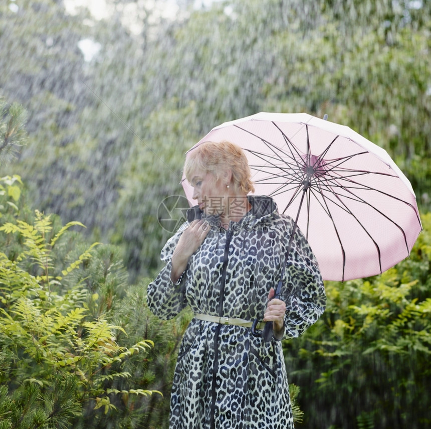 白色的身穿雨衣季夏日背景绿色自然的成熟女户外50年代图片