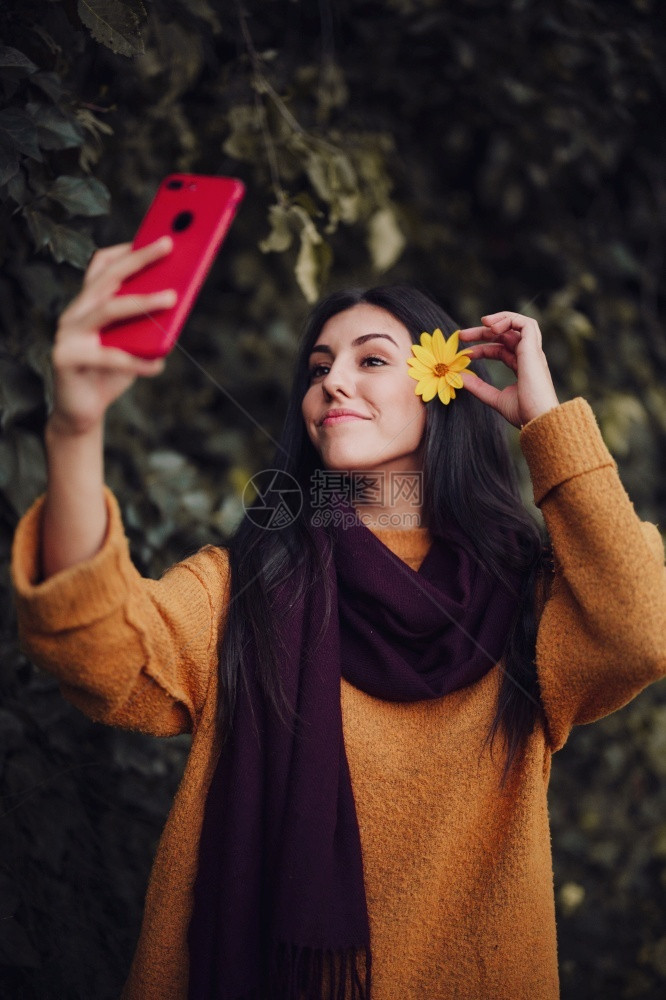 女人用手机拍自头发上插着花朵电话年轻的漂亮图片