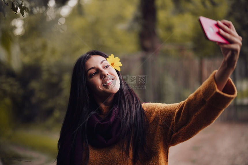 围巾女人用手机拍自头发上插着花朵服用外部图片