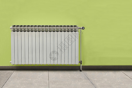 绿色墙前的白散热器目寒冷调节器图片
