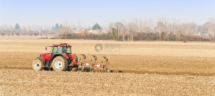 农业劳工红色拖拉机耕田场地准备一种图片