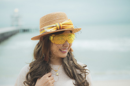 身着黄色眼镜站在海边的美丽亚洲女头部照片泰国美丽的帽子图片