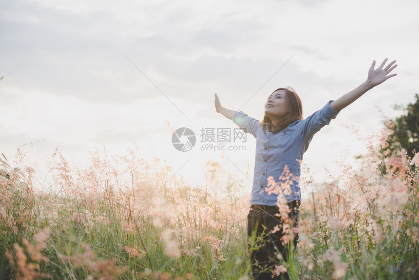 女年轻美丽的士站在草原上举起双臂在空中露出青草地日落时与大自然相享受天空黄色的图片