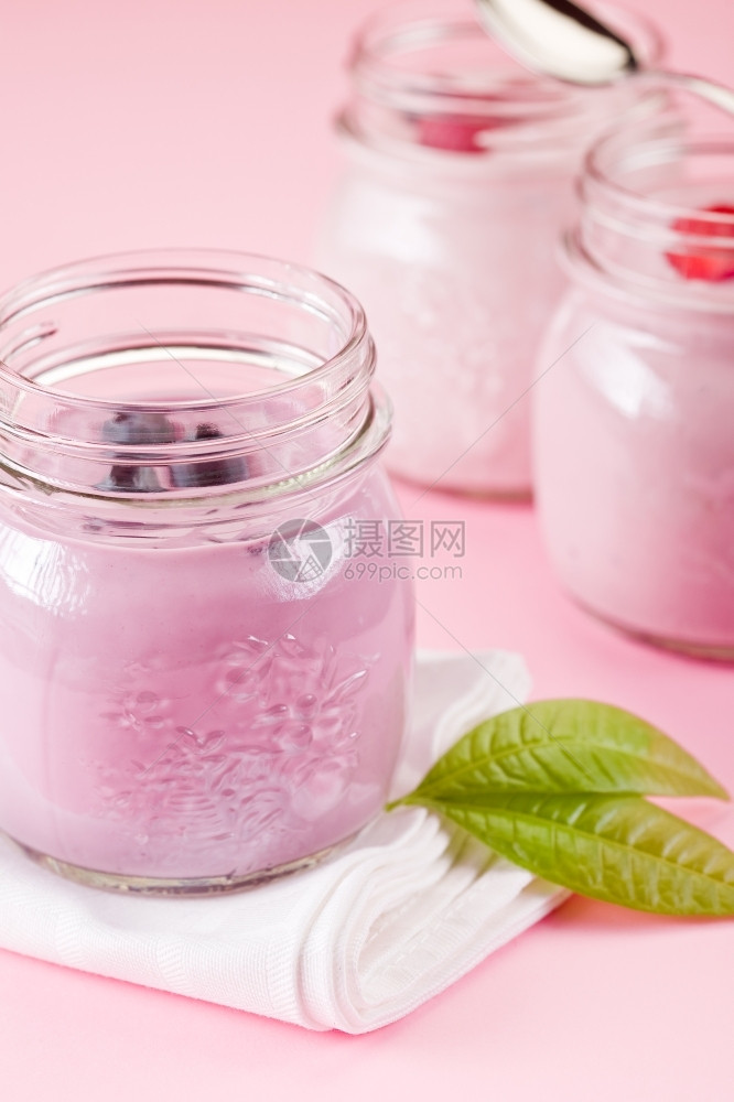 蓝莓玻璃浆果小罐子有酸奶在玫瑰背景和叶子上图片