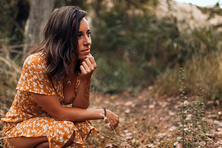 年轻的一种微笑女士穿着裙子在森林里蹲漂亮的图片