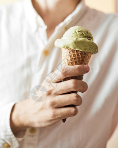 保持冷冻可选择的手握着一个冰淇淋锥子绿色茶叶的红冰淇淋锥子图片
