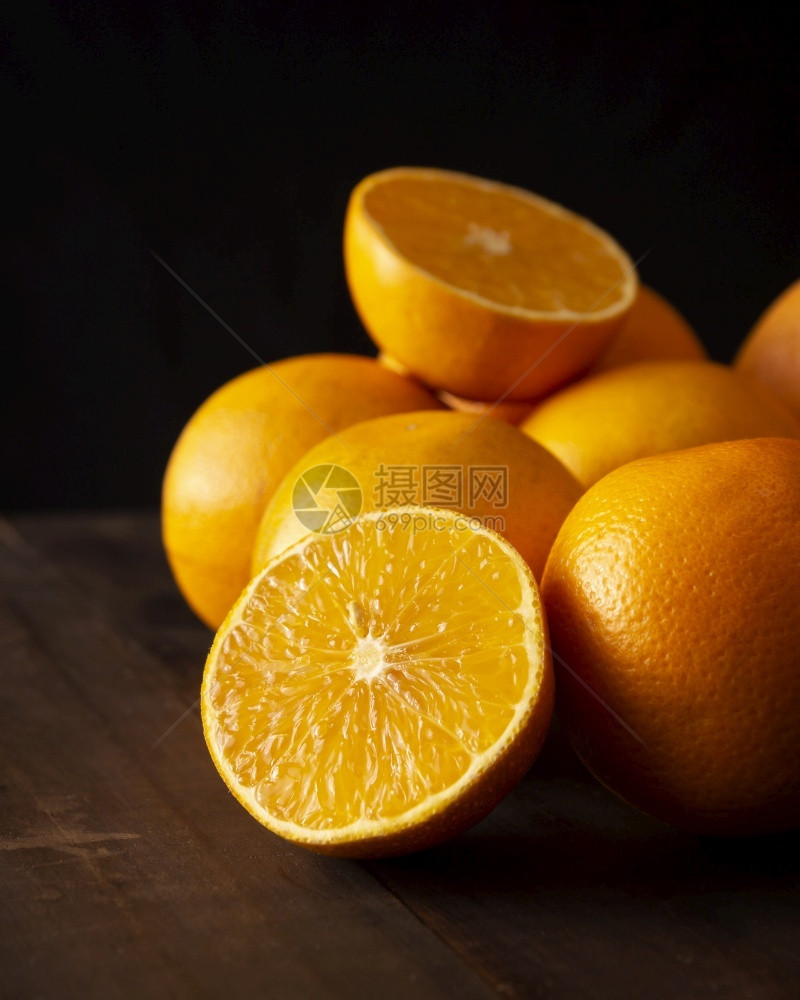 自然团体柑橘味在黑色背景的棕生皮木制桌上将熟橙子切成两半图片