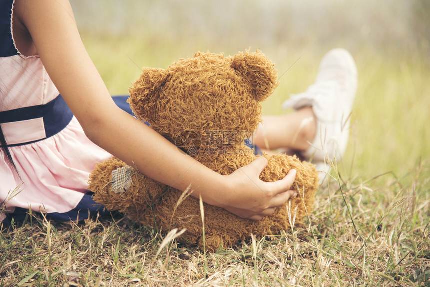 小女孩抱着一只毛茸的泰迪熊图片