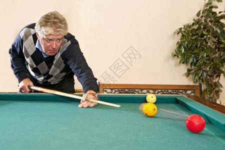 软垫高年长者玩木马球游戏有选择地关注标牌球的比赛运动在室内背景图片