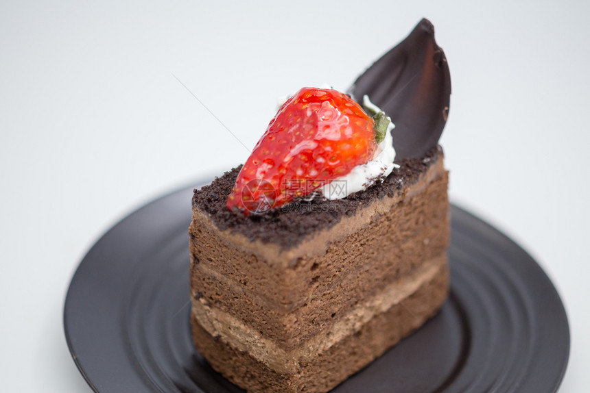 吃甜的巧克力蛋糕切片和白桌上黑沙盘中的草莓可图片
