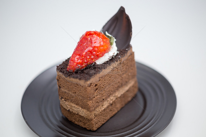 桌子经过小吃巧克力蛋糕的切片和白桌上黑沙盘中的草莓图片