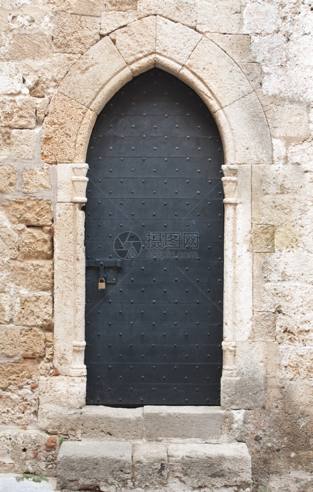 古董地中海螺栓石灰岩墙上的旧黑色木制中世纪门有古老的滑动门锁和挂图片