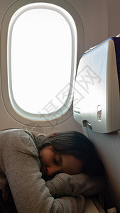 窗户年轻女孩睡在飞机上坐着眠图片