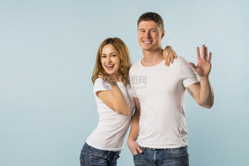 笑着微的年轻夫妇在蓝背景下挥手肖像最佳人们图片