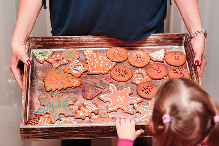 涂层家庭手工制作的小女孩在看盘子上满了圣诞烤姜饼干形各异图片