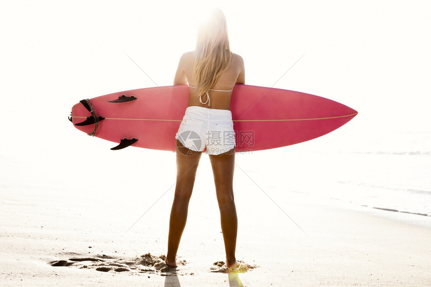 美女带着冲浪板在沙滩上图片