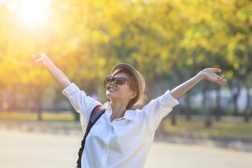 快乐的身着白衬衫和太阳眼镜的年轻女青在普尔比克公园中举起手来年轻的白色图片