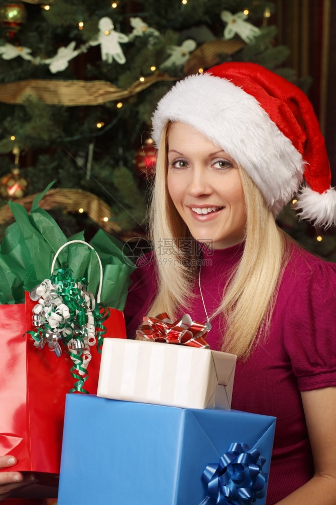 一位美丽的金发女郎坐在圣诞树前拿着礼物的相片照假期一种坐着图片