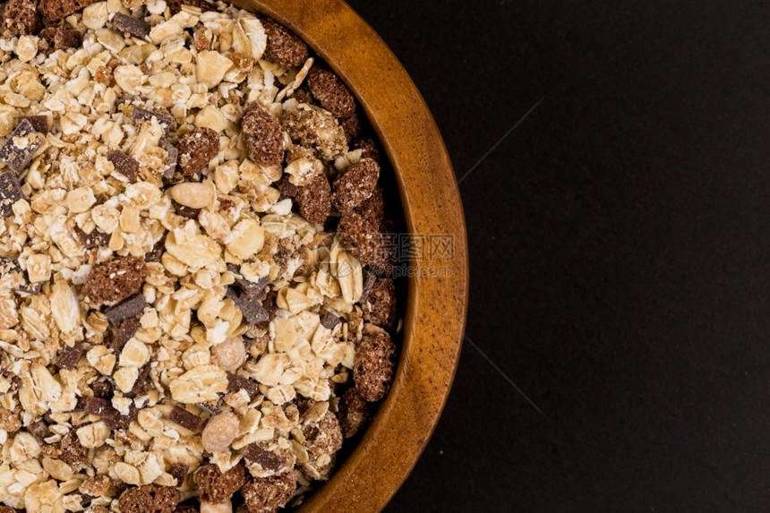 健康的燕麦谷物黑石上碗里有巧克力的黑暗薄片色图片