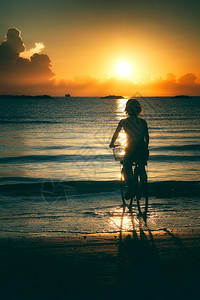 男人女孩在日出时海中骑自行车生活闲暇图片