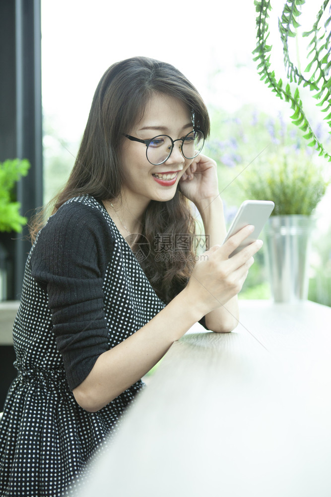 身体连接美丽的年轻亚洲女人笑着微的牙齿面对快乐的情感在智能手机上阅读信息假期图片